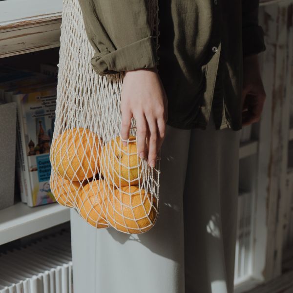 Person holding reusable string bag with fruit.