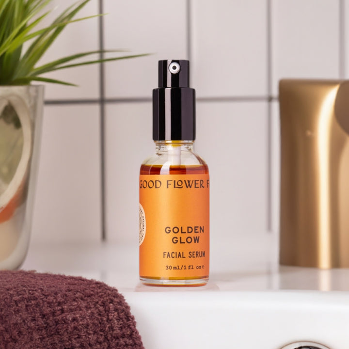 Golden Glow Facial Serum in glass bottle on bath vanity.