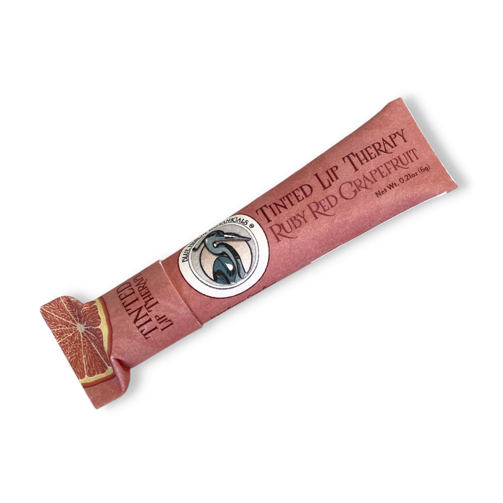 Blue Heron Botanical Lip Therapy Balm in Ruby Red Grapefruit formula (tinted), packaged in red compostable paper tube.
