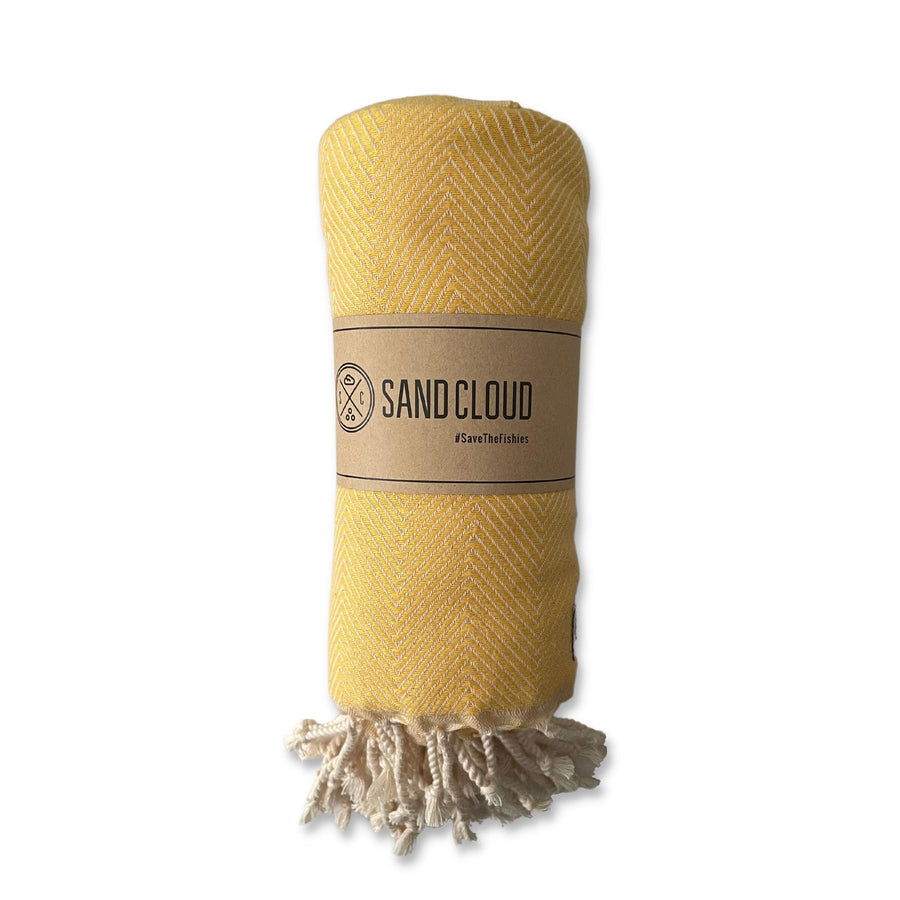 Turkish cotton travel towel in yellow color with natural fringe, shown in kraft paper sleeve (for packaging).