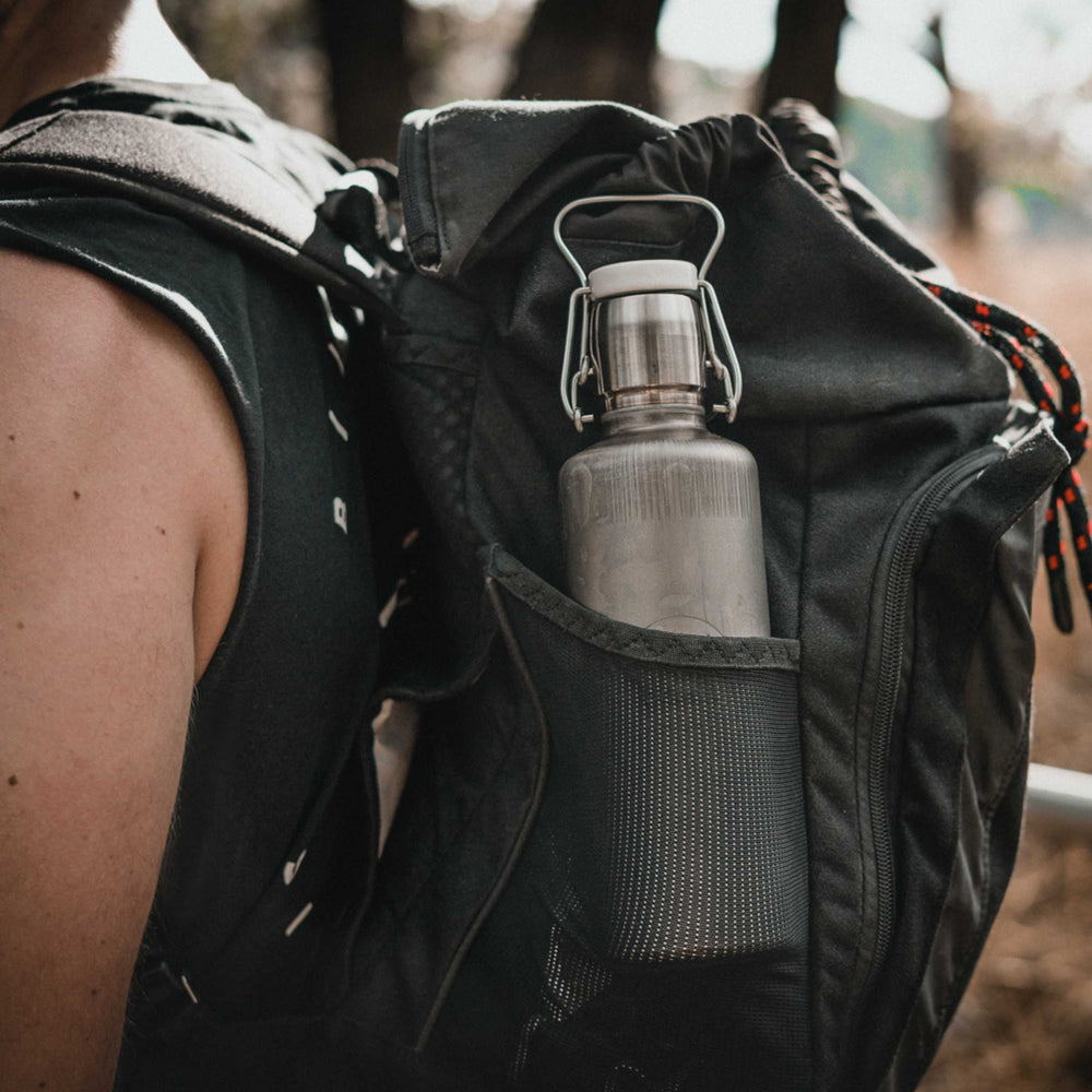 Soulbottles 20 ounce stainless steel insulated bottle in Industrial design, shown in backpack pocket on person's back.