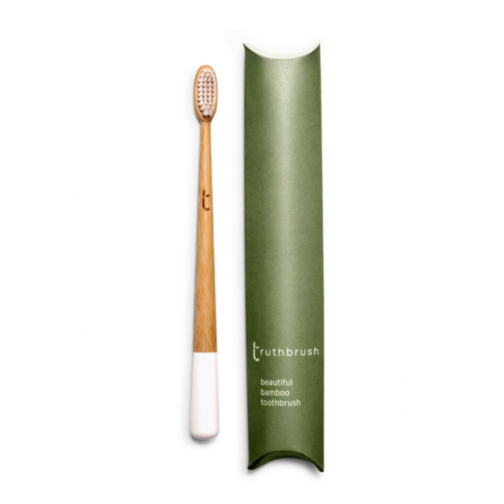 Truthbrush adult toothbrush in Cloud White color with medium bristles . Shown with plastic free packaging on right.